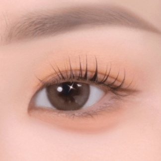 Close-up of an eye with soft, natural eye shadow enhancing the eyelid and long, curled lashes for a gentle look