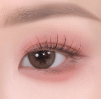 Close-up of eye featuring soft-textured pink eyeshadow enhancing natural lashes with subtle shimmer highlights