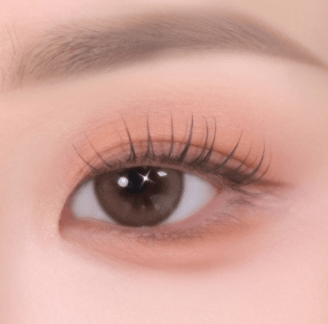 Close-up of a brown eye with soft-textured peachy eye shadow and natural-looking curled eyelashes