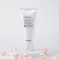 White tube of gentle brightening peeling gel elevated on round platform surrounded by soft pink pearl-like spheres