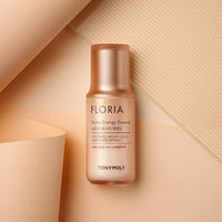 Matte peach-colored bottle of hydrating essence with argan oil and safflower extract on beige textured background