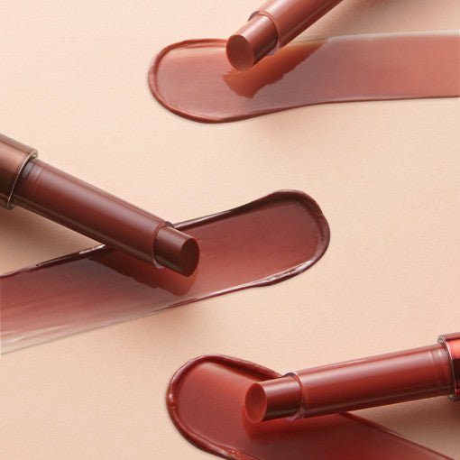 Three lip tint balms in warm brown tones with smooth glossy swatches on a neutral background