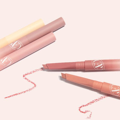 Three soft-toned lip liners with angled tips showing pigment lines on pale pink background