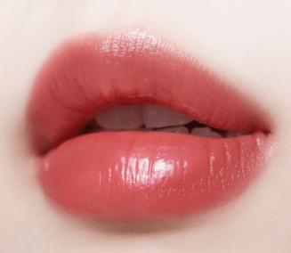 Close-up of lips with glossy coral tint showcasing smooth, hydrated finish emphasizing moisture retention benefits