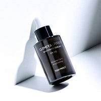 Black dropper bottle of brightening serum focusing on melanin care and blemish reduction benefits on white surface