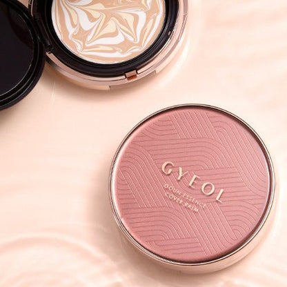 Compact cushion foundation with swirling beige and white tone and pink embossed cover labeled for high-coverage balm