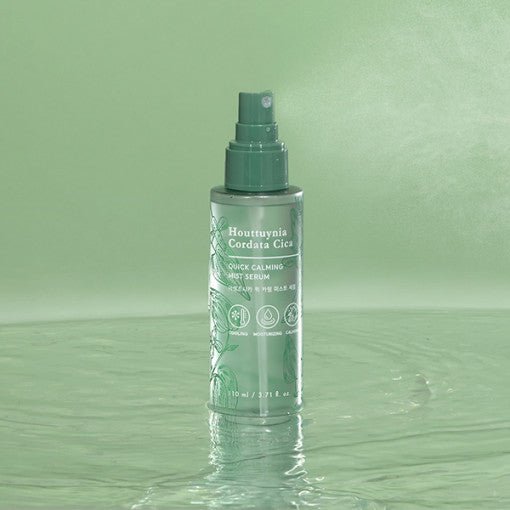 Green spray bottle of calming mist serum standing on water surface with botanical-inspired label design
