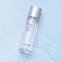 Clear skincare essence bottle with silver cap on rippled light blue surface highlighting enhanced elasticity benefits