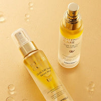 Two golden serum mist bottles with clear caps resting on a hydrated surface highlighting deep hydration benefits