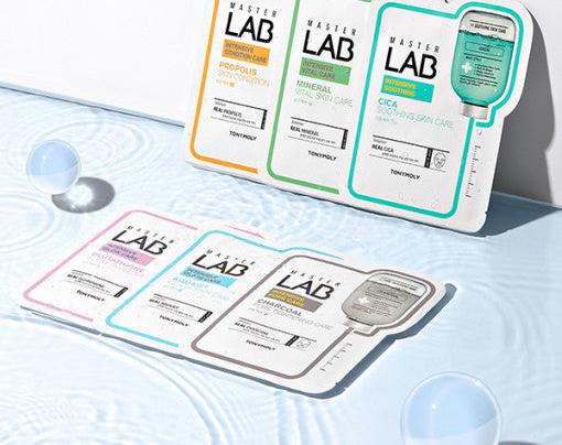Assorted Master Lab skincare sheet masks displayed on textured surface with water ripple and clear spheres