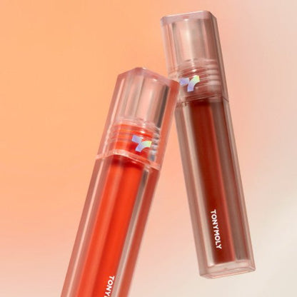 Two translucent lip tint tubes in warm red and brown shades with clear caps on peach background