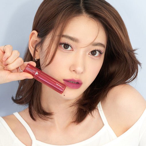 Young woman with natural makeup holding a red lip product emphasizing long-lasting color effect