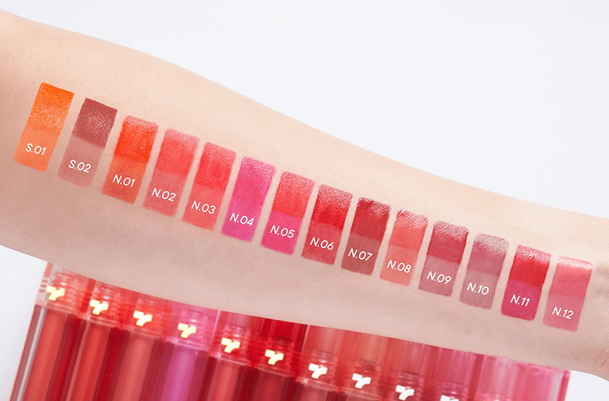 Arm swatches of 14 vibrant lip colors in warm and cool tones demonstrating long-lasting formula benefits