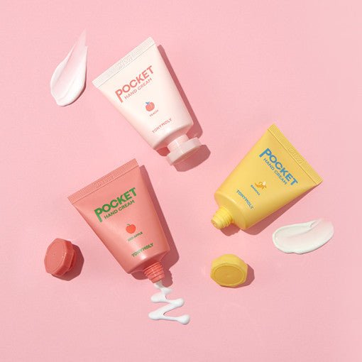 Three colorful tubes of nourishing hand cream with creamy swatches on pastel pink background