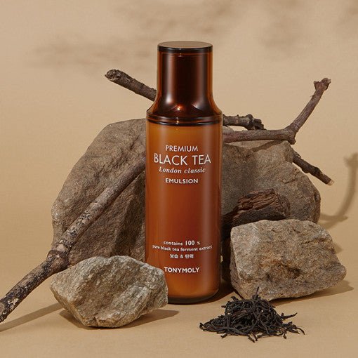 Amber bottle of emulsion with black tea leaves and natural stones emphasizing hydration and classic skincare benefits