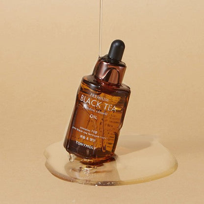 Amber dropper bottle of antioxidant-rich black tea oil with smooth liquid pooling on beige surface