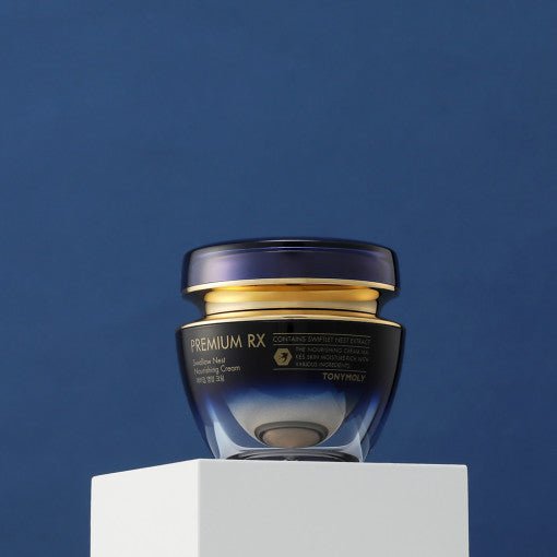 Elegant dark blue jar of nourishing cream with gold lid placed on white pedestal against deep blue background