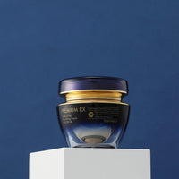 Dark blue and gold jar of nourishing cream with moisturizing benefits against deep blue background on white pedestal