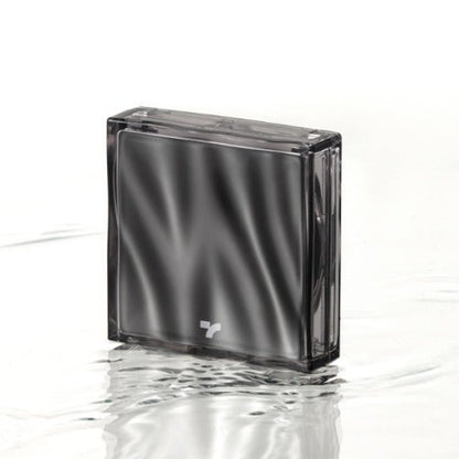 Compact black cushion foundation case with subtle wave reflections standing on rippled water surface