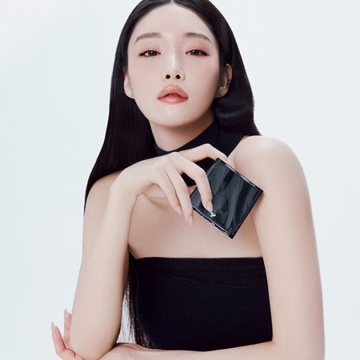 Woman with flawless complexion and sleek hair holding a compact cushion foundation case against white background