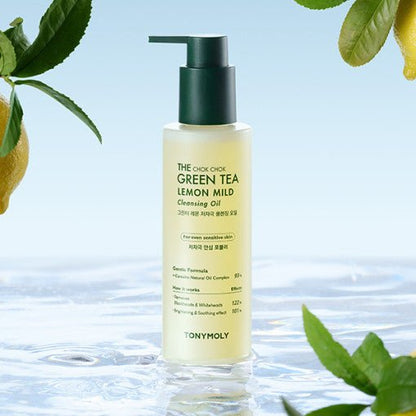 Clear bottle of mild green tea lemon cleansing oil with dark green pump surrounded by fresh leaves over water surface