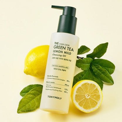 Pump bottle of gentle green tea lemon cleansing oil surrounded by fresh lemon halves and green leaves on soft background