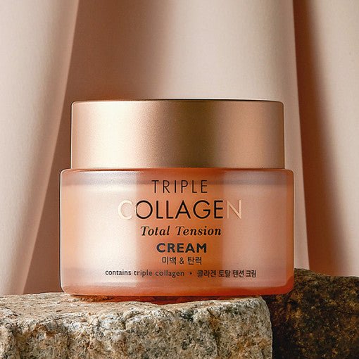 Frosted glass jar of moisturizing cream with rose gold lid placed on textured stone against soft beige background