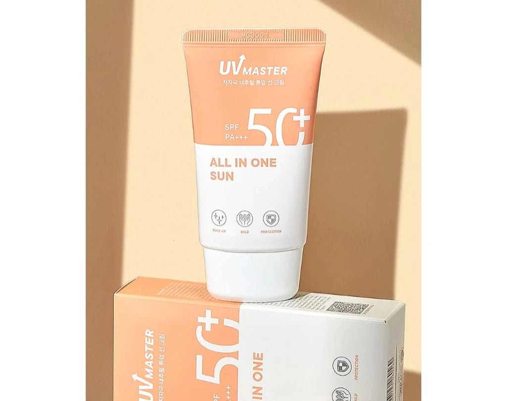 Tube of broad-spectrum SPF 50+ sunscreen resting on matching box in soft peach and white tones with protection icons visible