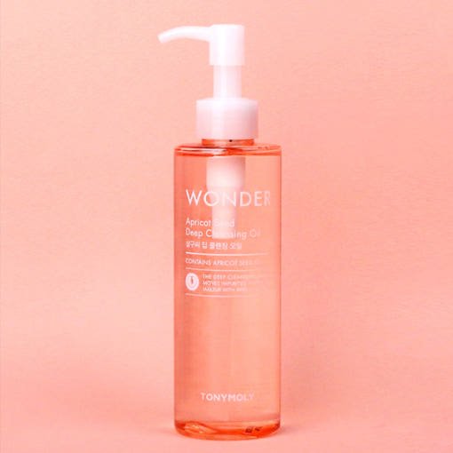 Clear pump bottle of apricot deep cleansing oil on peach background for gentle makeup removal