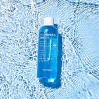 Blue toner bottle floating on clear rippling water surface highlighting hydration and refreshing care benefits