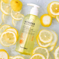 Clear pump bottle of brightening lemon Vitamin C toner surrounded by fresh lemon slices in water