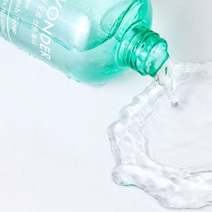 Green translucent toner bottle pouring clear liquid onto white surface with soft rippling effect