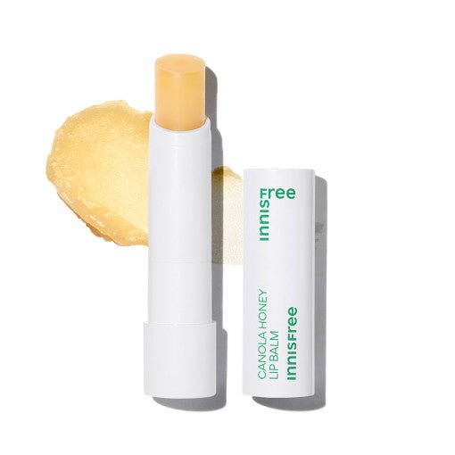Open white lip balm tube with pale yellow balm and honey-colored smear on white background
