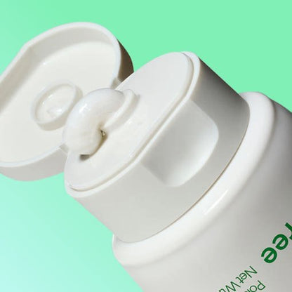 Close-up of white cleansing foam gently dispensed from white flip-top tube against light green background