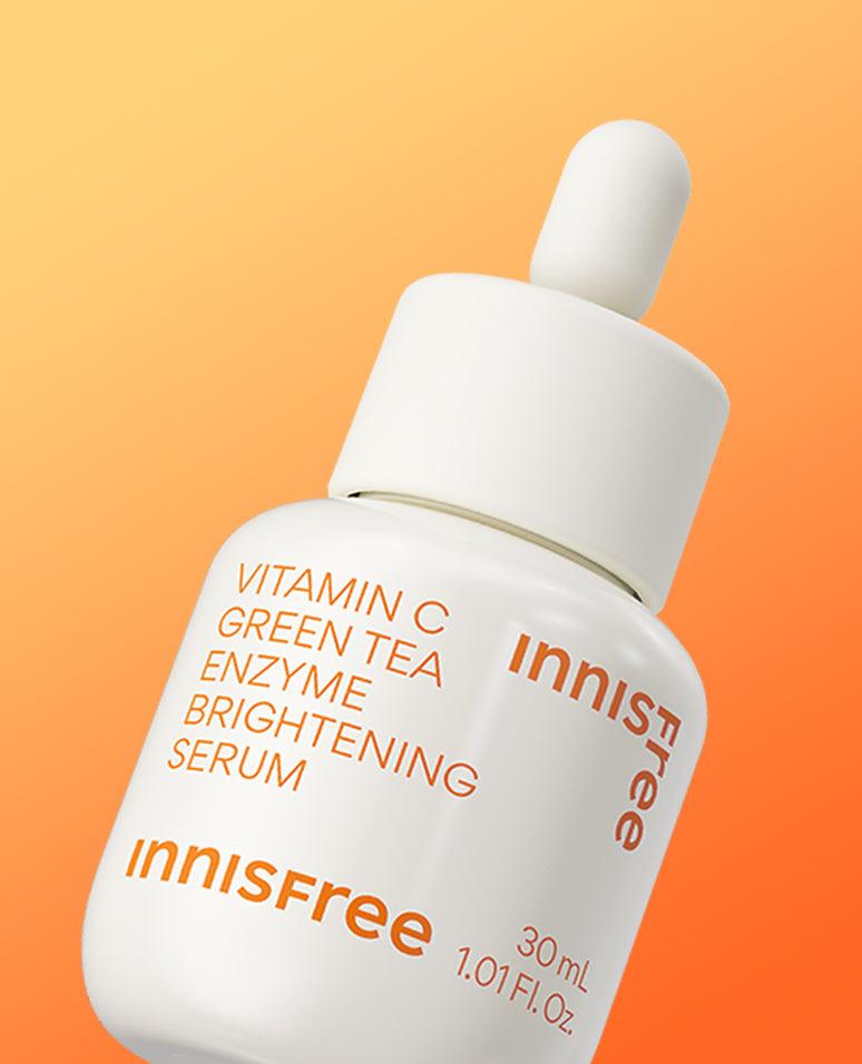 White dropper bottle of brightening serum with orange text against a warm gradient background