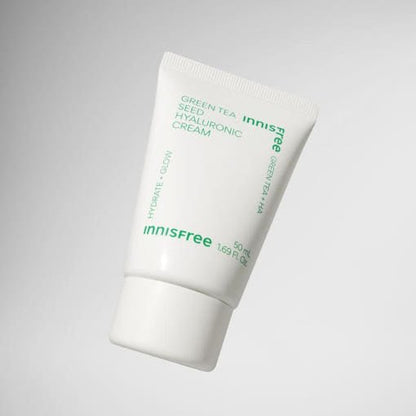 White tube of hydrating green tea seed hyaluronic cream with green text on a simple gray background