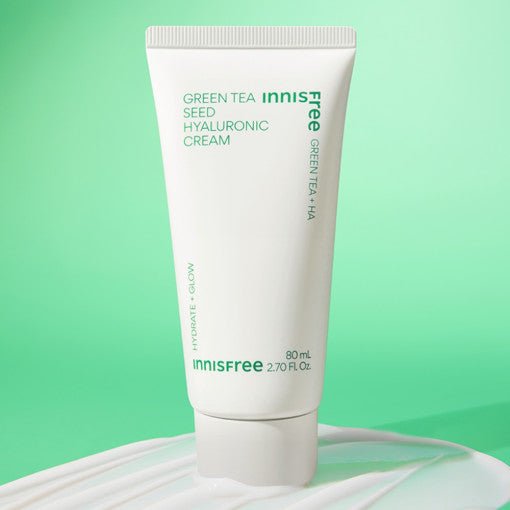 White squeeze tube of moisturizing cream with green text on pastel green background and cream spread underneath