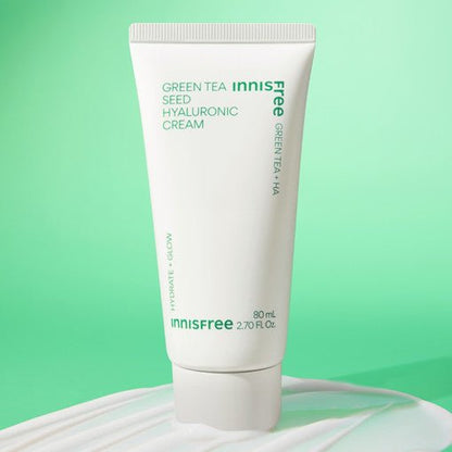 White squeeze tube of moisturizing cream with green text on pastel green background and cream spread underneath