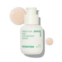 White bottle of hydrating serum with green text and two droplets of light beige serum on white background