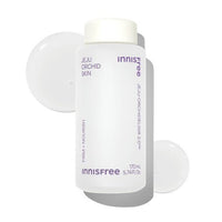 Minimalist white bottle of hydrating skin essence with orchid extract and clear liquid droplets on white background