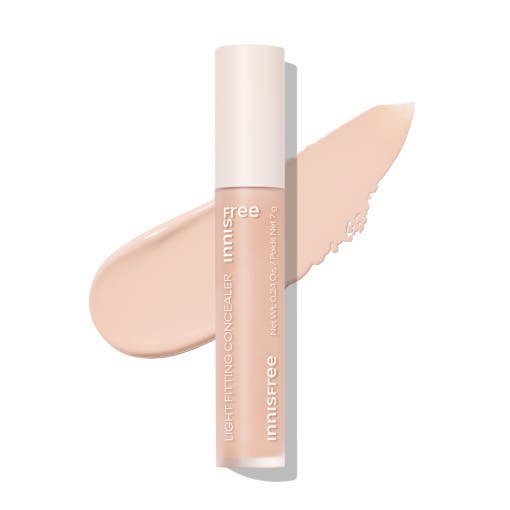 Tube of light fitting concealer in salmon beige shade with smooth swatch behind on white background