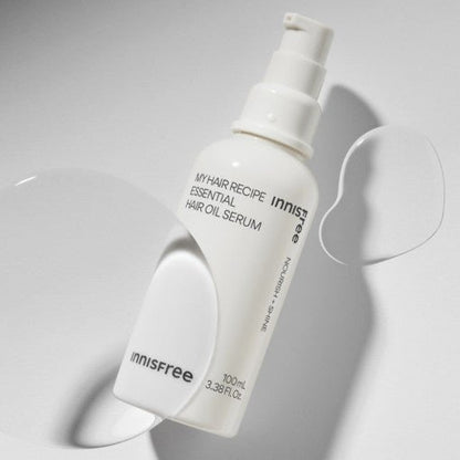 White pump bottle of nourishing hair oil serum with smooth translucent drops on light background