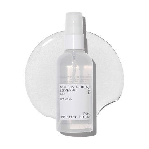 Clear spray bottle of refreshing body and hair mist with subtle pink coral label on a white textured background