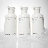 Three white pump bottles of innisfree perfumed body cleanser with foamy bubbles at the base on a white background