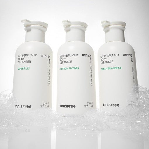 Three white bottles of innisfree body cleanser in Water Lily, Cotton Flower, and Green Tangerine scents surrounded by soft foam bubbles