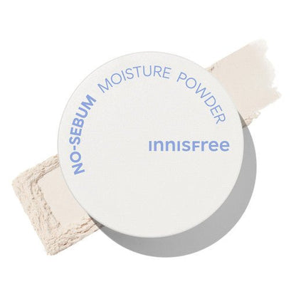 White container of moisture powder with blue text placed on beige powder swatch showing matte finish and oil control benefits