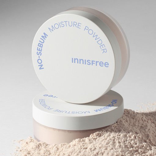 White container of no-sebum moisture powder with loose light beige powder spilled beside it on gray background