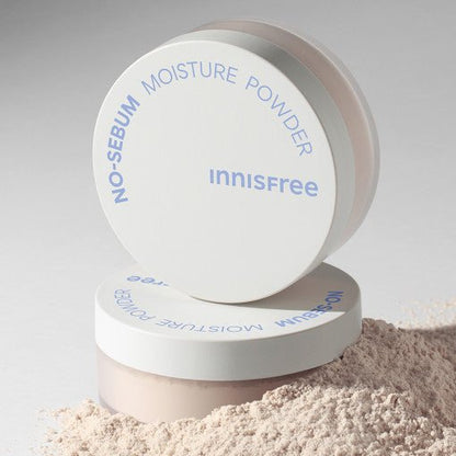 White container of no-sebum moisture powder with loose light beige powder spilled beside it on gray background
