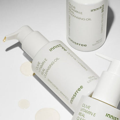 White pump bottles of olive vitamin E cleansing oil with moisturizing formula on a light neutral background