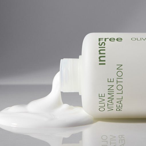 Creamy white lotion pouring from a white bottle with green text promoting moisture boost and vitamin E benefits